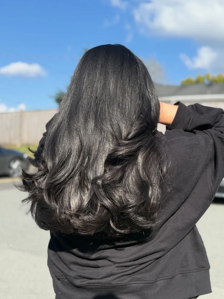 Glossy black hair with soft curls and volume by Lux Hair Surrey